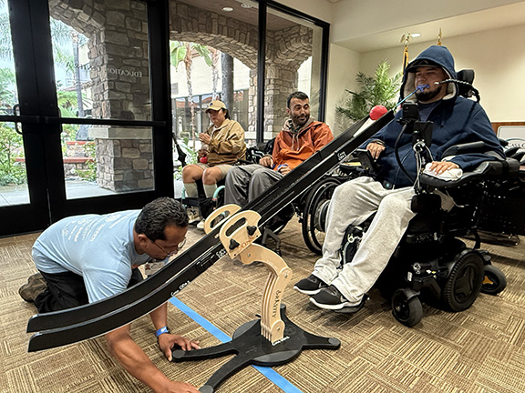 man in wheelchair using a ramp to roll a boccia ball
