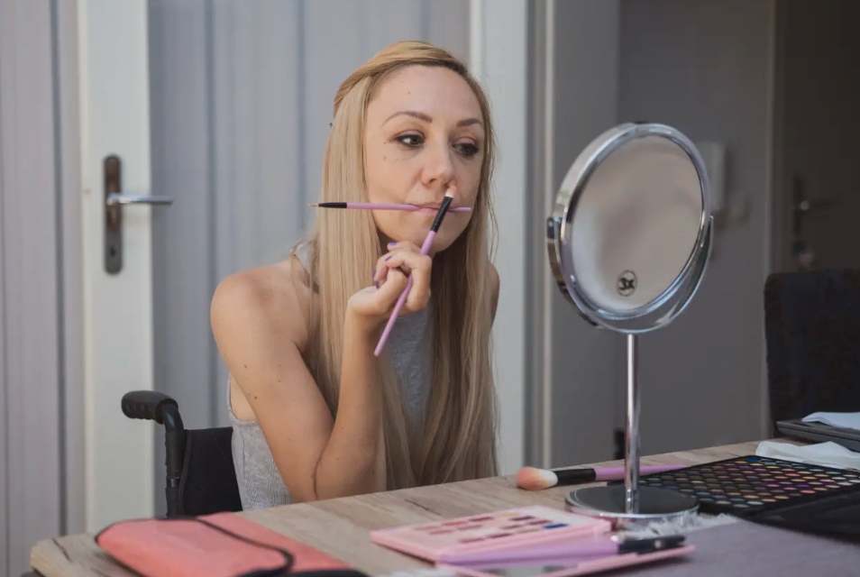 Woman looking in mirror and applying makeup